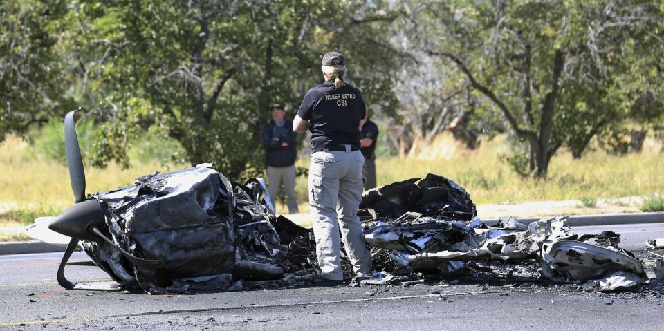 A investigator looks at the wreckage of a small plane that struck a car when it crashed into a neighborhood in Roy, Utah on Sept. 12, 2017.