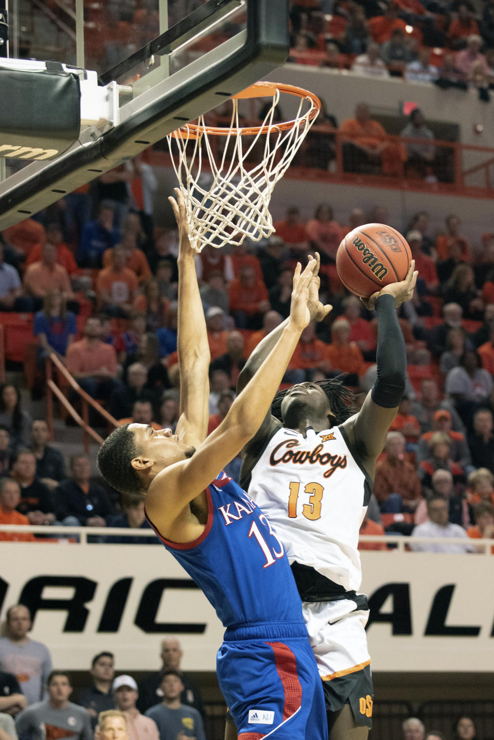 Oklahoma State guard Isaac Likekele (13) takes a shut under pressure from Kansas guard Tristan Enaruna (13) during the first half of an NCAA college basketball game in Stillwater, Okla., Monday, Jan. 27, 2020. (AP Photo/Brody Schmidt)