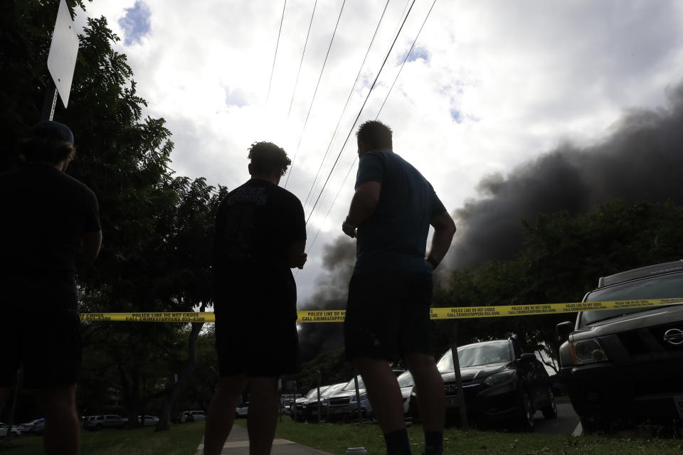 Bystanders watch black smoke billowing from a house fire after a shooting and domestic incident at a residence on Hibiscus Road near Diamond Head on Sunday, Jan. 19, 2020, in Honolulu. Witnesses say at least two Honolulu police officers were shot and two civilians were injured. Moments after the shooting, the house was set on fire, possibly by the suspect. (Jamm Aquino/Honolulu Star-Advertiser via AP)