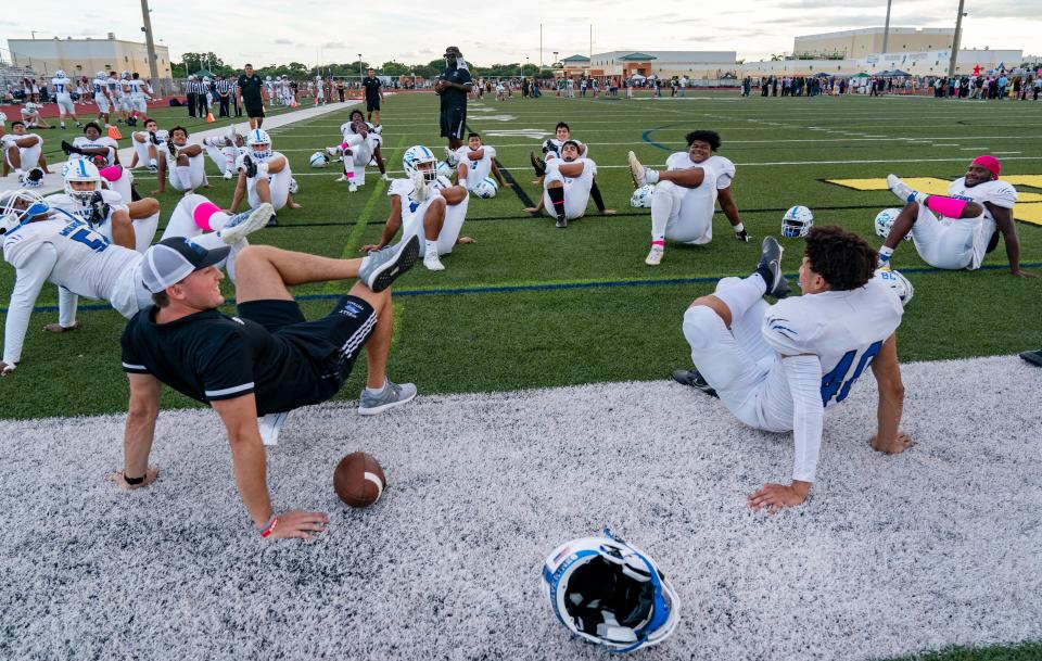 Wellington High School football players stretch on an artificial turf field before their game against the Warriors in Jupiter in 2021. Jupiter and Wellington high schools are two of the three high schools that have artificial fields.