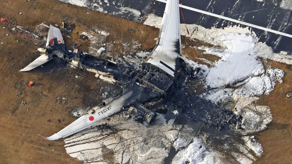 This aerial photo show the burn-out Japan Airlines plane at Haneda airport on January 3, 2024, in Tokyo, Japan. - Kyodo News/AP