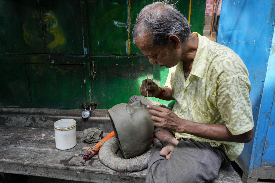 An artisan works on an idol of Hindu goddess Durga ahead of Durga Puja festival at Kumortuli, the potters' place, in Kolkata, India, Sept. 18, 2022. The five-day festival commemorates the slaying of a demon king by goddess Durga, marking the triumph of good over evil. (AP Photo/Bikas Das)