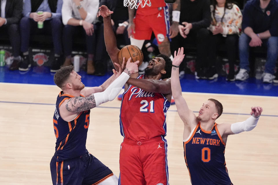 New York Knicks' Isaiah Hartenstein, left, and Donte DiVincenzo, right, defend against Philadelphia 76ers' Joel Embiid (21) during the second half of Game 2 in an NBA basketball first-round playoff series Monday, April 22, 2024, in New York. (AP Photo/Frank Franklin II)