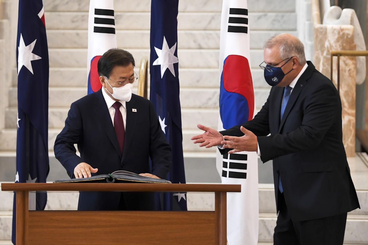 South Korean President Moon Jae-in, left, is invited to sign a visitors book by Australian Prime Minister Scott Morrison at Parliament House, in Canberra, Australia, Monday, Dec. 13, 2021. Moon is on a two-day official visit to Australia. (Lukas Coch/Pool Photo via AP)