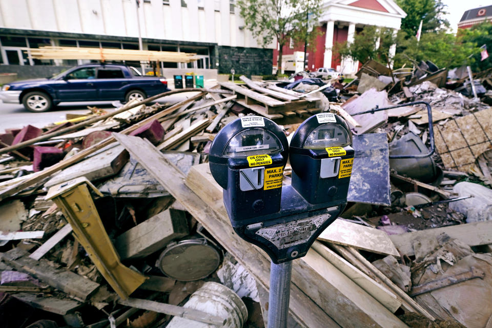 Flooding debris is stacked along State Street, near the state capital building, as a vehicle drives past with a load of lumber tied to the roof in downtown, Tuesday, Aug. 1, 2023, in Montpelier, Vt. The mostly gutted shops, restaurants and businesses that lend downtown Montpelier its charm are considering where and how to rebuild in an era when extreme weather is occurring more often. Vermont's flooding was just one of several major flood events around the globe this summer that scientists have said are becoming more likely due to climate change. (AP Photo/Charles Krupa)