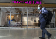 An international traveler walks past a closed store at the Los Angeles International Airport in Los Angeles Wednesday, Nov. 25, 2020. Residents were urged to avoid nonessential travel during what is typically the busiest travel period of the year. Anyone entering California was advised to quarantine for two weeks. (AP Photo/Damian Dovarganes)