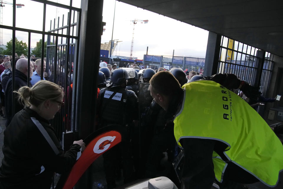 Police and stewards block one of the entrances to the Stade de France prior to the Champions League final soccer match between Liverpool and Real Madrid, in Saint Denis near Paris, Saturday, May 28, 2022. Police have deployed tear gas on supporters waiting in long lines to get into the Stade de France for the Champions League final between Liverpool and Real Madrid that was delayed by 37 minutes while security struggled to cope with the vast crowd and fans climbing over fences. (AP Photo/Christophe Ena)