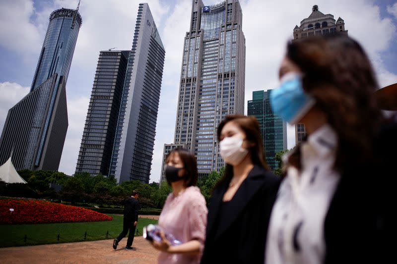 People wearing protective face masks walk at Lujiazui financial district on the opening day of the National People's Congress (NPC), in Pudong, Shanghai