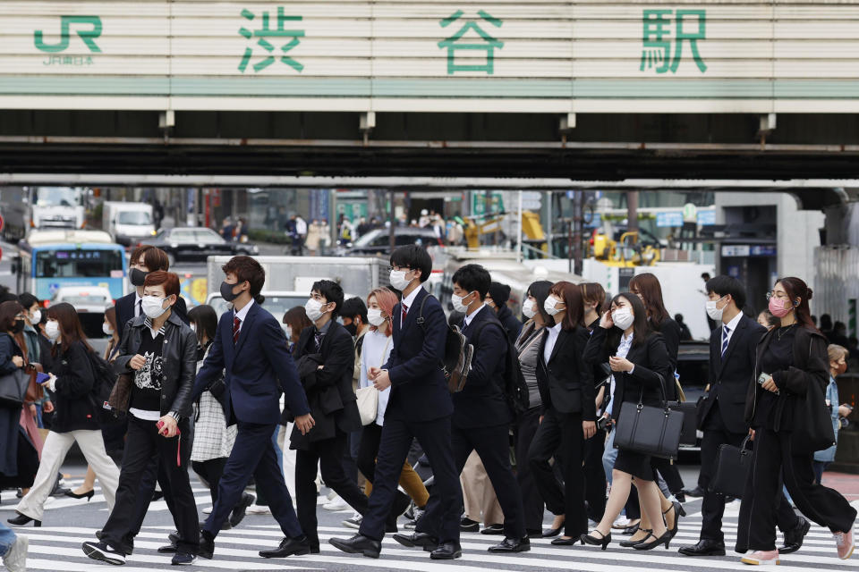 People wearing face masks cross an intersection in the downtown in Tokyo, Japan, Thursday, April 8, 2021. Tokyo, the capital of Japan, has asked the central government for permission to implement emergency measures to curb a surge in a rapidly spreading and more contagious coronavirus variant, just over three months before the start of the Olympics. (Kyodo News via AP)