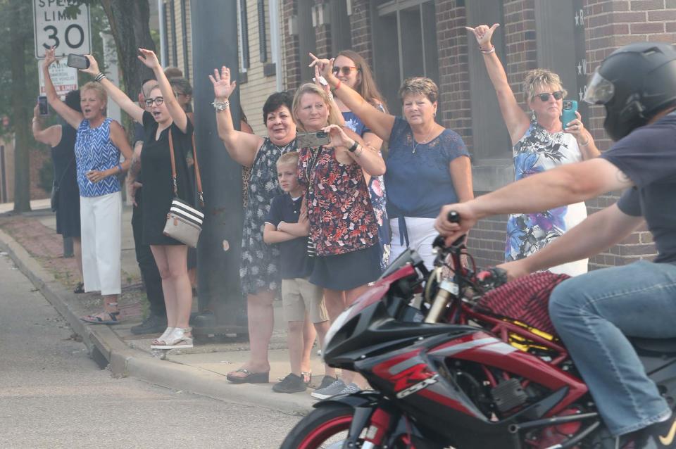 The family of Matthew Parisi show their appreciation of the motorcyclists in attendance as a large group rides by at the conclusion of the calling hours Sunday.