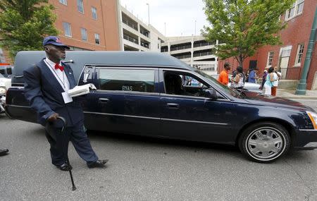 A preacher reading scripture from his bible walks next to the hearse of legendary guitarist B.B. King as he leaves Beal Street during a procession in honor of the blues musician in Memphis, Tennessee May 27, 2015. - RTX1ETTX