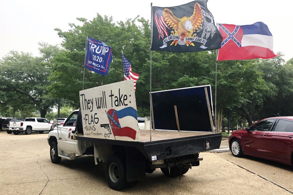 Joe Brister of Madison, Miss., pauses briefly in the parking lot of the Mississippi Capitol on Friday, June 26, 2020, in Jackson, Miss. Brister says he wants to keep the Confederate battle emblem on the Mississippi state flag, which is shown on the large sign on the truck. (AP Photo/Emily Wagster Pettus)