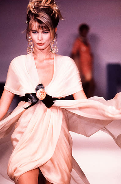 1989 – Au défilé Chanel printemps-été 1989-1990, elle est âgée de 19 ans et impressionne déjà sur le catwalk. Sa robe drapée lui apporte un style aérien, retenue astucieusement par une ceinture pour sculpter sa silhouette.