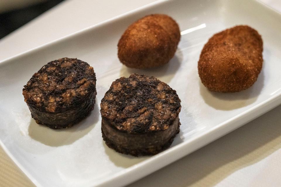 A small plate of croquettes and black sausage.