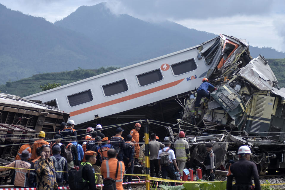 Rescuers inspect the wreckage after the collision between two trains in Cicalengka, West Java, Indonesia, Friday, Jan. 5, 2024. The trains collided on Indonesia's main island of Java on Friday, causing several carriages to buckle and overturn and killing at least a few people, officials said. (AP Photo/Abdan Syakura)