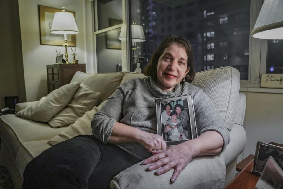 Anne D'Innocenzio shows a portrait of herself, right, with her sister, Donna Burke, left, and mother, Marie D'Innocenzio, as she sits on a sofa from her childhood home, Monday, Feb. 26, 2024, in New York. D'Innocenzio said, "After Mom's passing, my sister and I quickly made a plan to honor her wishes: what to keep, which items to give to relatives and friends, which basic items to donate — and what to just discard." (AP Photo/Bebeto Matthews)