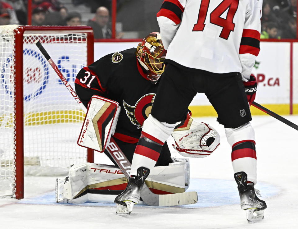 Ottawa Senators goaltender Anton Forsberg (31) makes a glove save in front of New Jersey Devils right wing Nathan Bastian (14) during first period of an NHL hockey game in Ottawa, on Saturday, Nov. 19, 2022. (Justin Tang /The Canadian Press via AP)