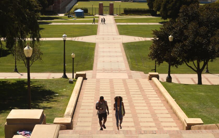 LOS ANGELES, CA - AUGUST 05, 2020 - - Chedeya Brown, 20, right, who graduated from UCLA this past Spring, and her cousin Christian Call, 24, walk up the Janss Steps on a nearly empty UCLA campus in Los Angeles on August 13, 2020. Brown returned to the campus to have her photo taken for the school yearbook. She and her cousin were going to make their own photos at the top of the stairs. The empty campus is a preview of what the Fall semester will look like. Most classes will be held online at the university due to the coronavirus pandemic. (Genaro Molina / Los Angeles Times)