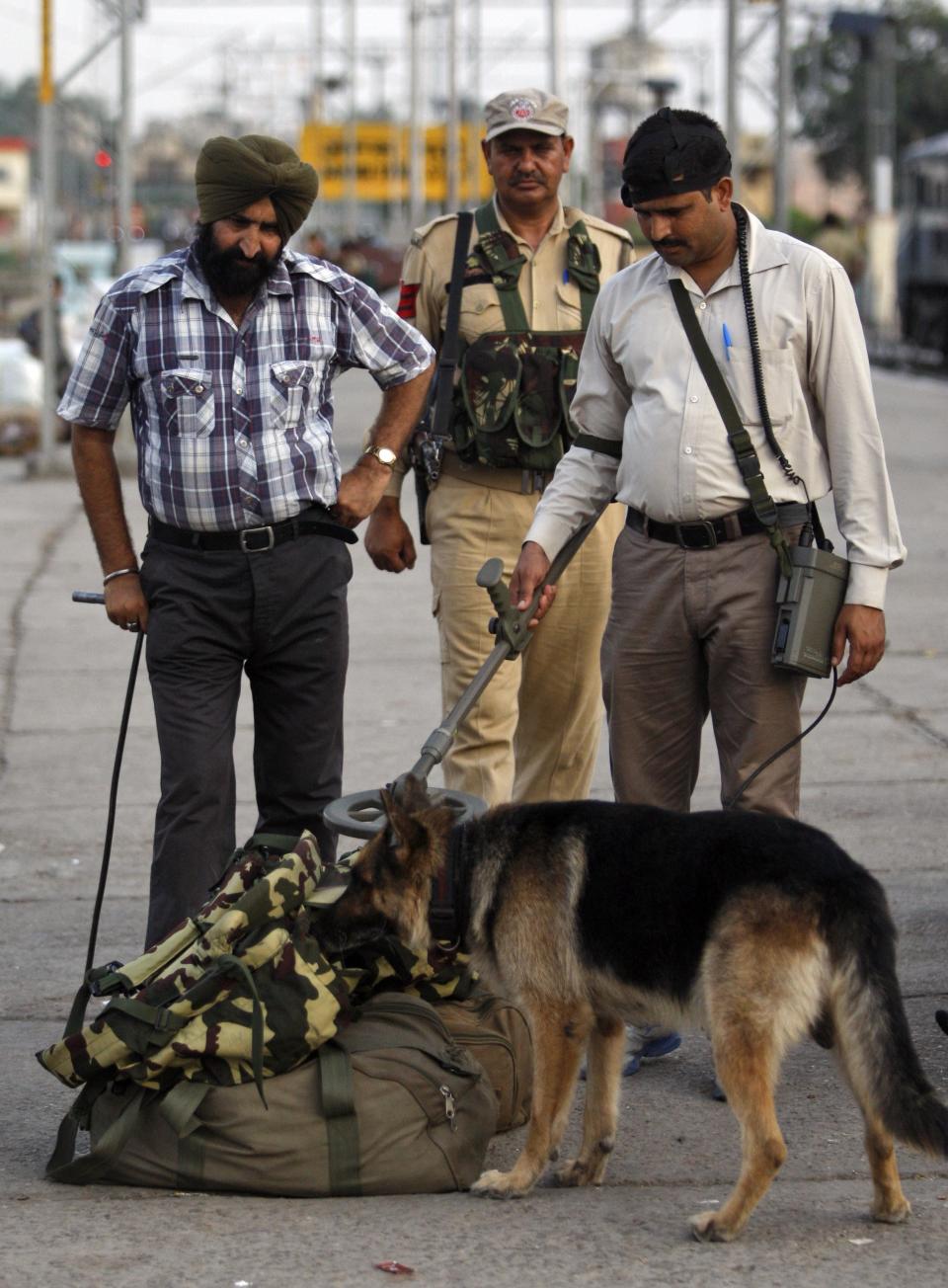 Security officers, along with a sniffer dog, inspect luggage at a railway station in Jammu, india, Thursday, July 3, 2014. Security has been beefed up ahead of Indian prime minister Narendra Modiâs visit to the state of Jammu and Kashmir, Police said. (AP Photo/Channi Anand)