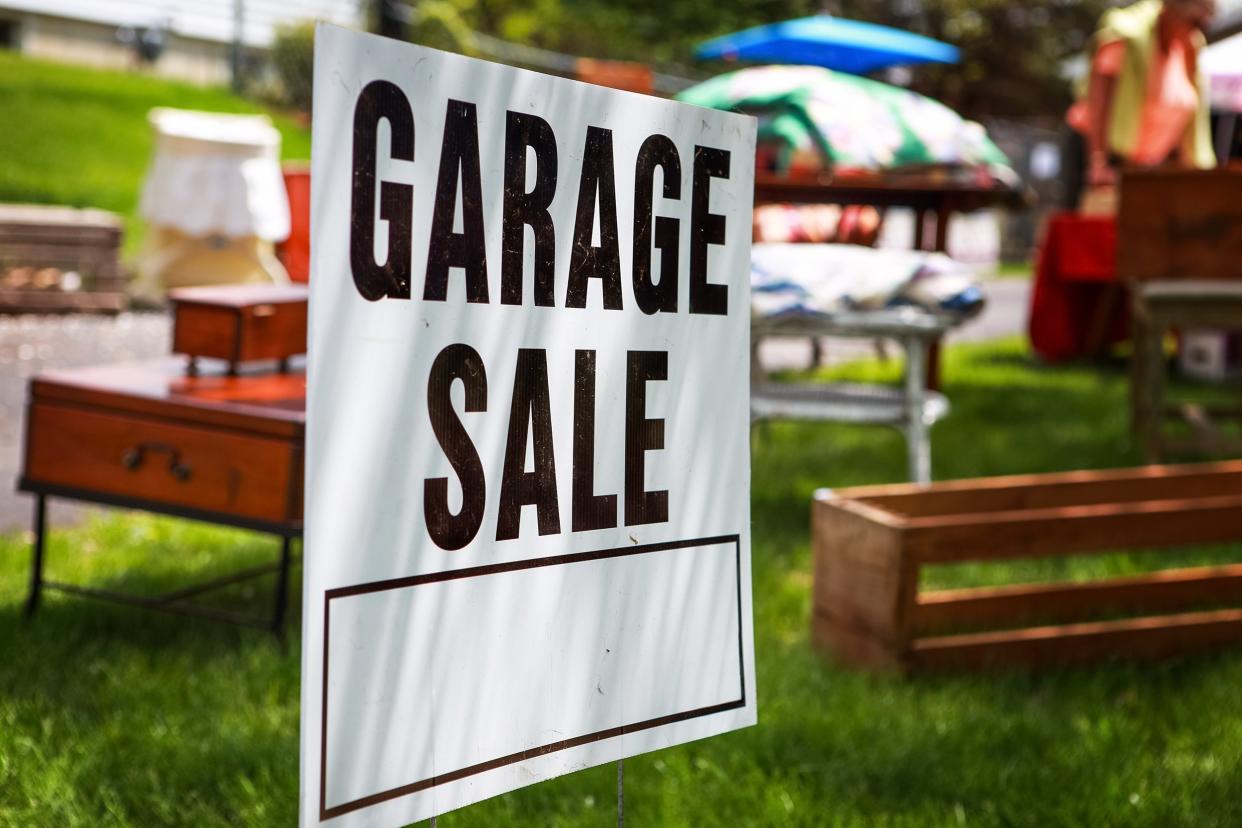 garage sale sign on the shady lawn of a suburban home