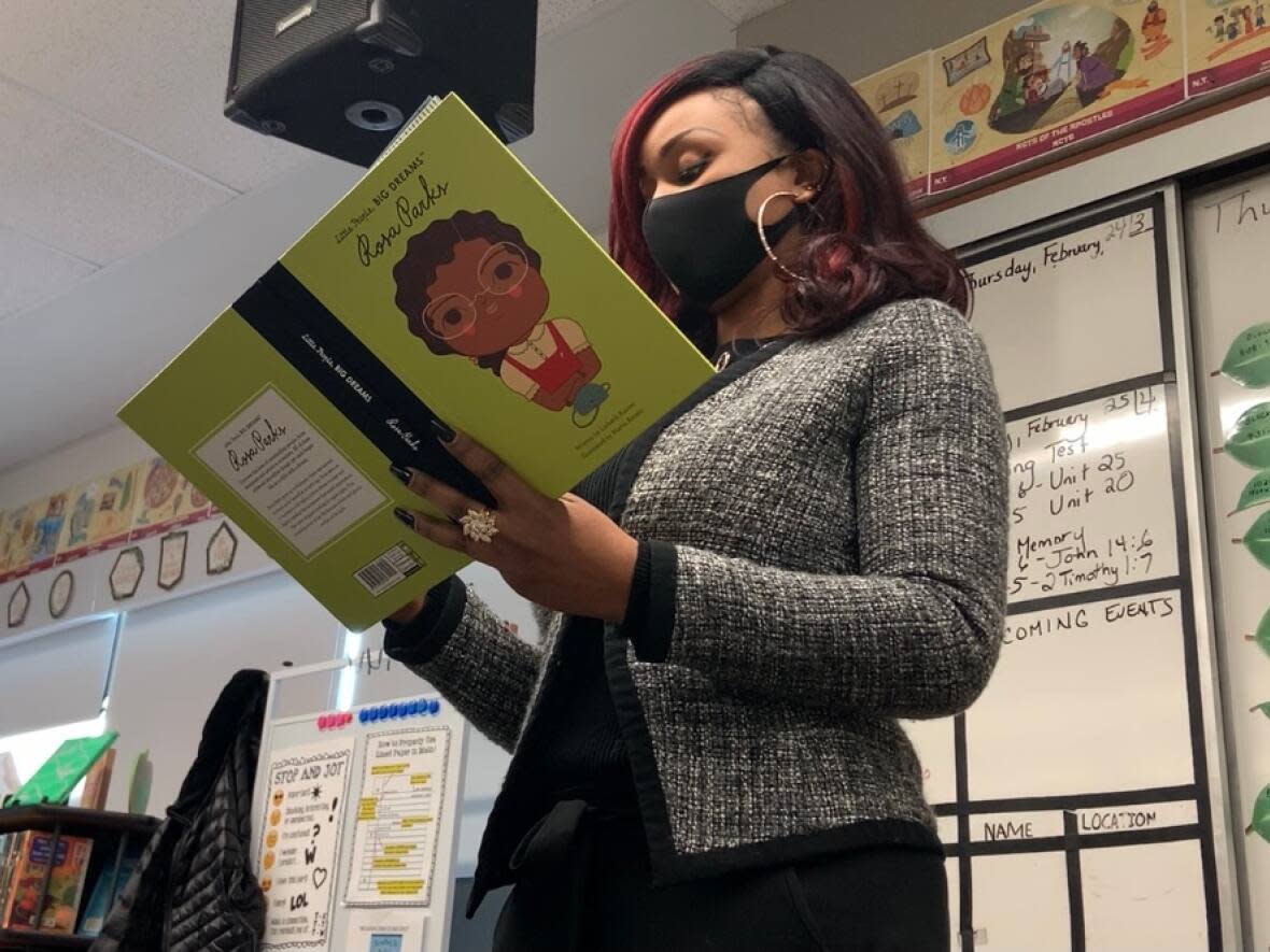 Jibs Abitoye, chair of the Fort Black Society in Fort Saskatchewan, Alta., reads to Grade 4 students at Fort Saskatchewan Christian School from one of the books the group donated to it for Black History Month. (Gabriela Panza-Beltrandi/CBC - image credit)