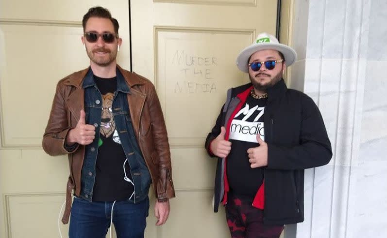 During the Jan. 6 siege of the Capitol, Nicholas Ochs, left, and Nicholas DeCarlo pose in front of a door upon which the name of their right-wing online streaming outlet, Murder the Media, is scratched.