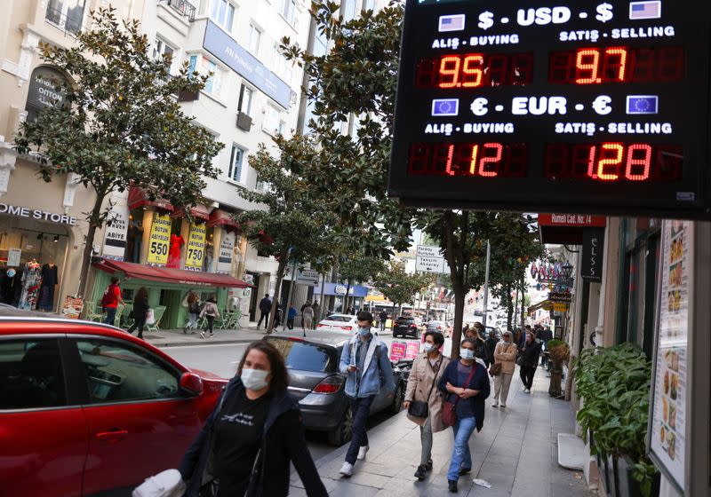 People walk past a currency exchange office sign in Istanbul