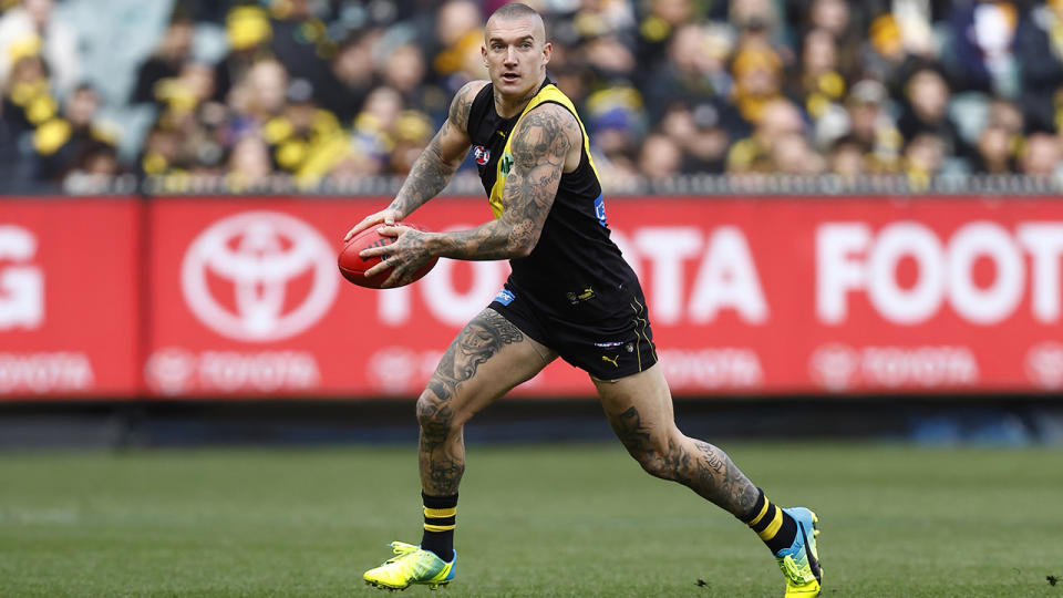 Dustin Martin surveys the field and carries the ball during an AFL game.