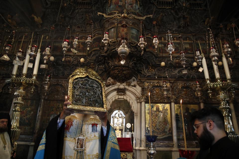 Metropolitan Dorotheos of Syros and Tinos lifts an icon believed to perform miracles during a service in the Holy Church of Panagia, on the Aegean island of Tinos, Greece, on Thursday, Aug. 13, 2020. For nearly 200 years, Greek Orthodox faithful have flocked to Tinos for the August 15 feast day of the Assumption of the Virgin Mary, the most revered religious holiday in the Orthodox calendar after Easter. But this year there was no procession, the ceremony _ like so many lives across the globe _ upended by the coronavirus pandemic. (AP Photo/Thanassis Stavrakis)