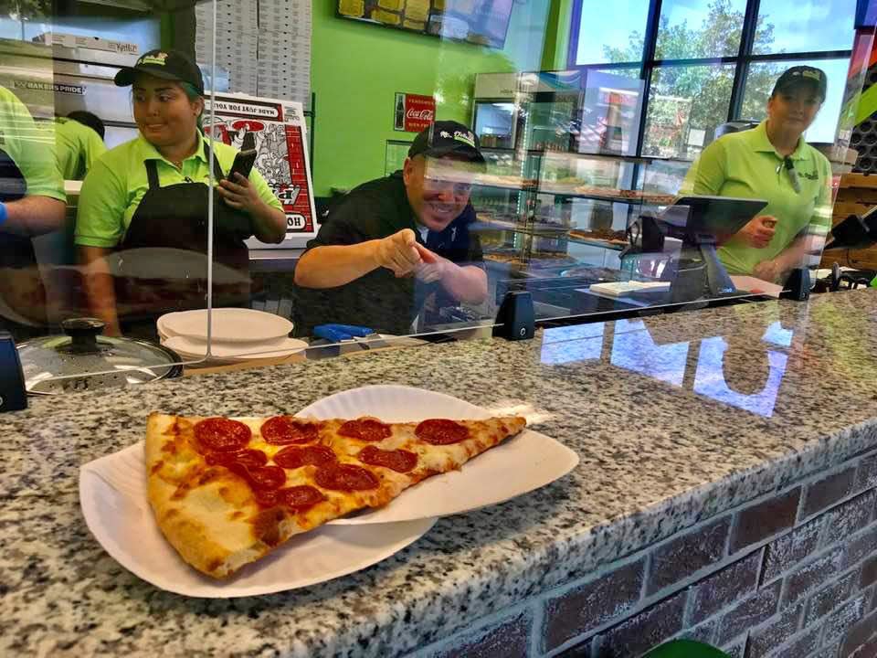 Mr. Delicious Pizza owner Mike Acosta, center, greets a customer Monday, the day the new Viera pizzeria opened. Mr. Delicious sells whole pizzas as well as giant pizza slices.