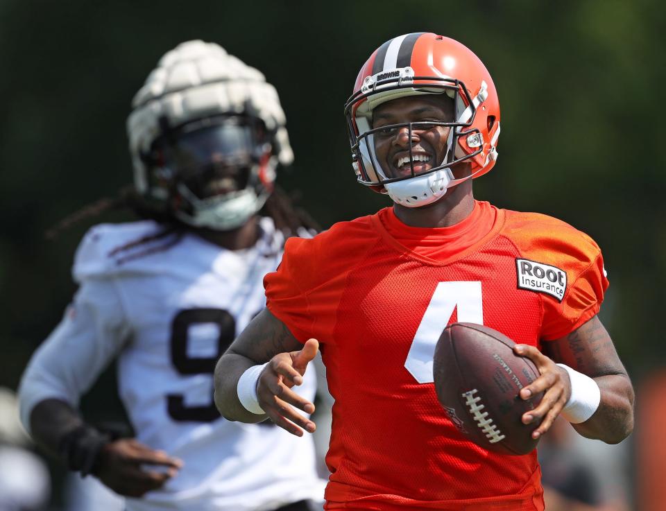 Cleveland Browns quarterback Deshaun Watson is all smiles as he rushes for a short gain ahead of defensive end Jadeveon Clowne during the NFL football team's football training camp in Berea on Wednesday.