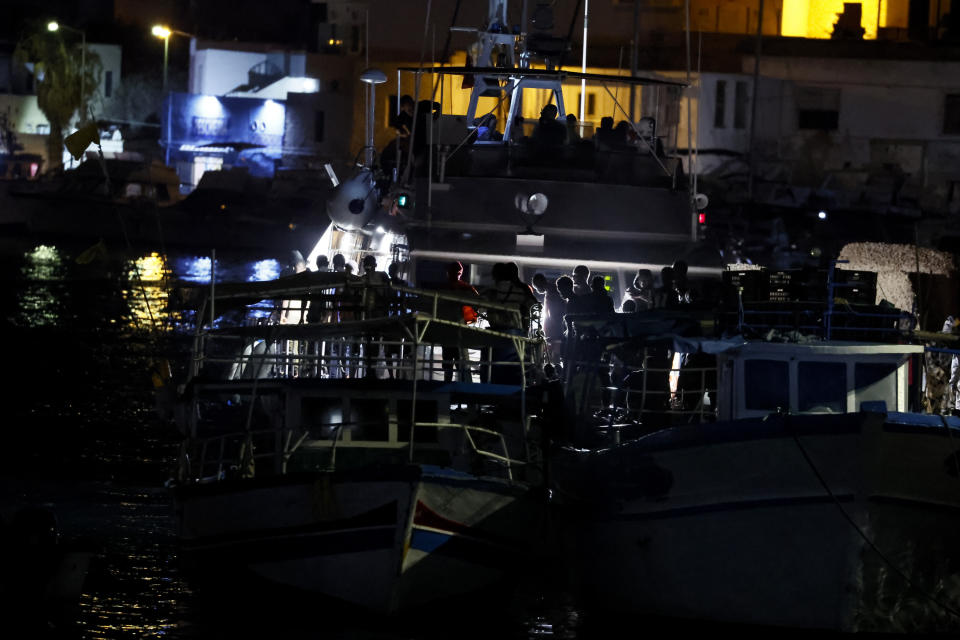 Rescued migrants disembark from a boat on the Italian island of Lampedusa during the evening of Saturday, Sept. 16, 2023. Tensions on the small island were rising Saturday, as both residents and migrants chafed at the long wait times to transfer people from the crowded reception center to the Italian mainland. Nearly 7,000 migrants arrived on Lampedusa from Tunisia this week, and the Red Cross said that 3,800 remained on the island on Friday. (Cecilia Fabiano/LaPresse via AP)