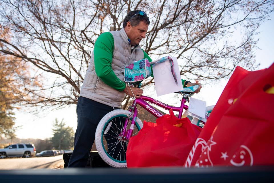 Brad Hughes, chair of the board of directors at YMCA of Greenville, loads a kids bike into a truck at YMCA of Greenville Metro Office before gifts are delivered to families in Greenville for Christmas on Friday, Dec. 15, 2023.