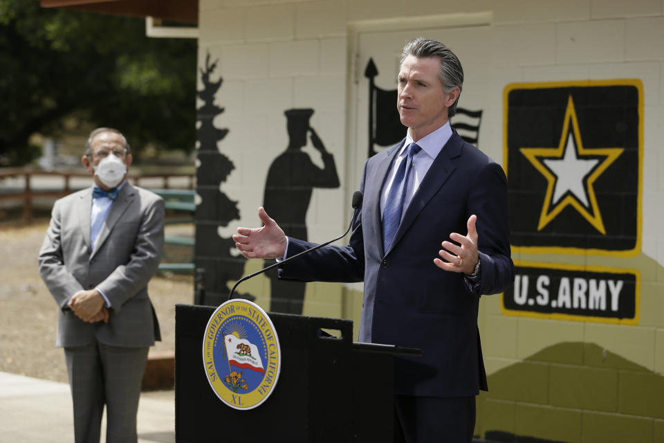 California Gov. Gavin Newsom gestures during a news conference as CalVet Secretary Vito Imbasciani looks on at the Veterans Home of California, Friday, May 22, 2020, in Yountville, Calif.