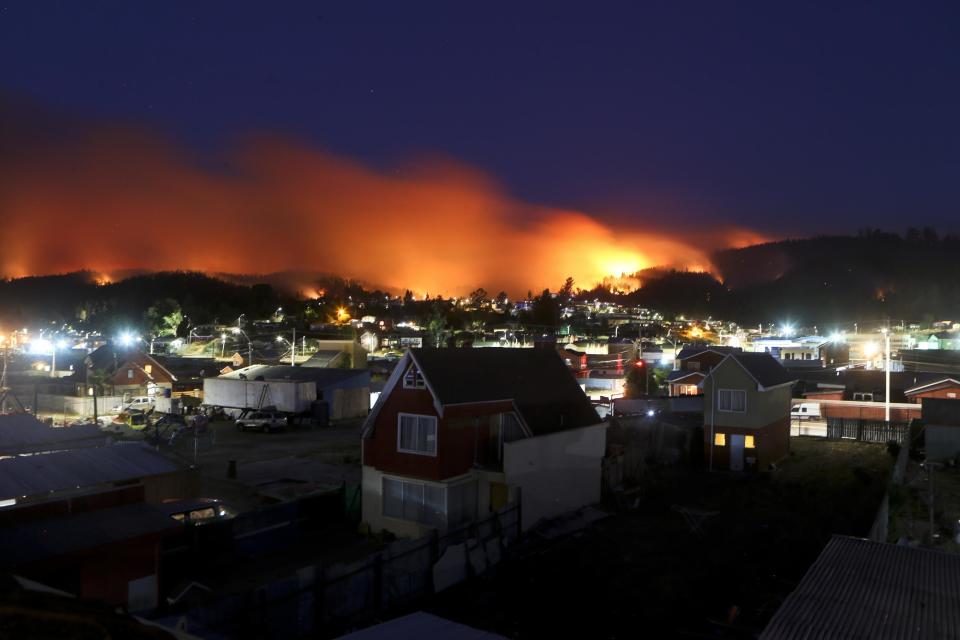 In this Monday, Jan. 30, 2017 photo, wildfires straddle Chile's Dichato community. Strong winds are continuing to stoke the flames of raging wildfires in Chile, forcing the evacuation of more than 800 families in the coastal town of Dichato. (AP Photo/Esteban Felix)