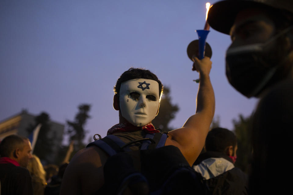 An Israeli anti-government protester wears a mask on the back of his head outside of the official residence of Prime Minister Benjamin Netanyahu on the day his corruption trial was originally scheduled before it was postponed, in Jerusalem, Wednesday, Jan. 13, 2021. (AP Photo/Maya Alleruzzo)