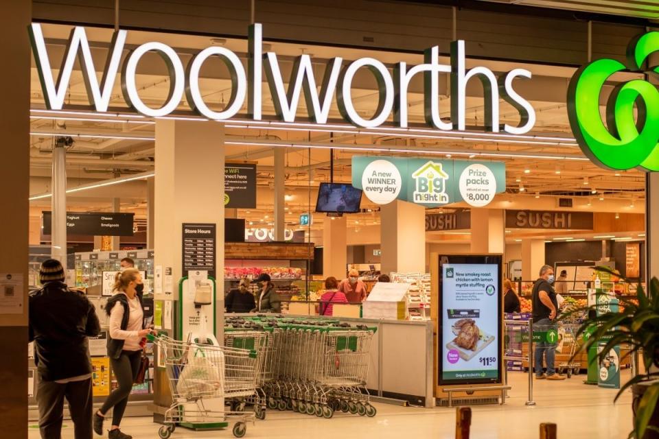 Woolworths shoppers exit supermarket with trolley full of groceries