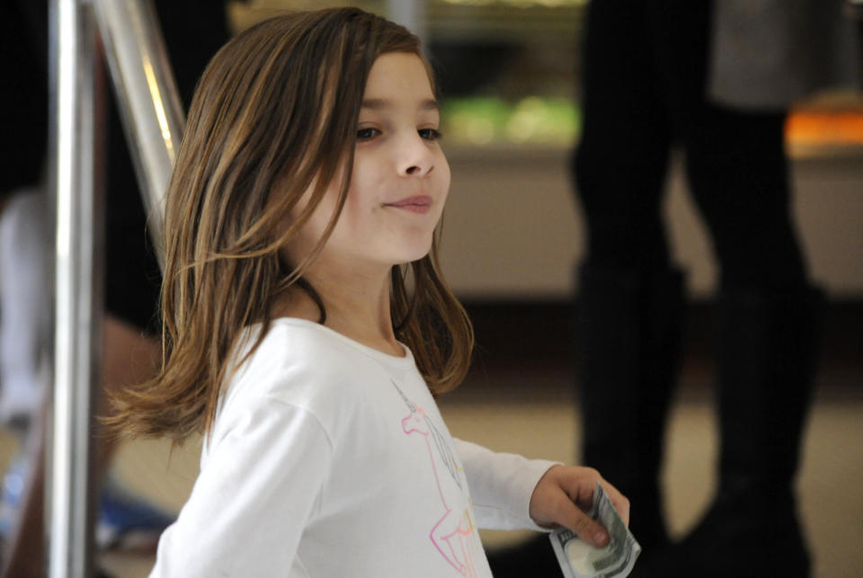 Liza Scott, who is running a lemonade stand to help fund her own brain surgery, holds a donation at her mother's bakery in Homewood, Ala., on Tuesday, March 2, 2021. Mother Elizabeth Scott said the family has good health insurance, but expenses are still high and the 7-year-old girl wanted to help out. The child was diagnosed with brain malformations following seizures earlier this year, her mother said. (AP Photo/Jay Reeves)