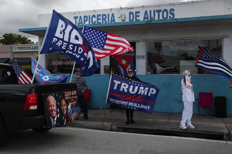 A caravan of supporters for Democratic presidential nominee Joe Biden drive past supporters of President Donald Trump standing on the sidewalk next to the Versailles Restaurant during a Worker Caravan for Biden event on Sunday in Miami.