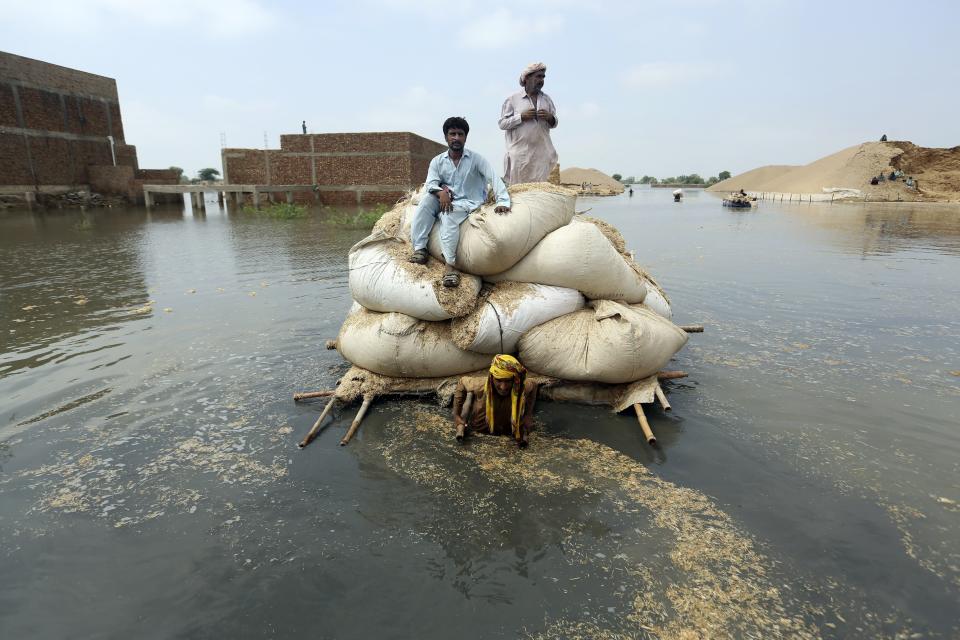 FILE - Victims of flooding from monsoon rains use a makeshift barge to carry hay for cattle, in Jaffarabad, a district of Pakistan's southwestern Baluchistan province, Sept. 5, 2022. The flooding in Pakistan killed at least 1,700 people, destroyed millions of homes, wiped out swathes of farmland, and caused billions of dollars in economic losses. (AP Photo/Fareed Khan, File)