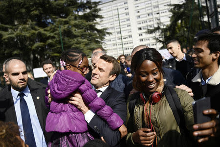 Emmanuel Macron (C), head of the political movement En Marche !, or Onwards !, and candidate for the 2017 presidential election, holds a girl during a campaign visit in Sarcelles, near Paris, April 27, 2017. REUTERS/Martin Bureau