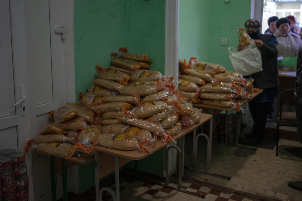 Volunteers distribute bread rations to civilians waiting at a public school in MykolaivTuesday, Oct. 25, 2022. Mykolaiv residents pick up bread from the only food distribution point in Varvarivka, a Mykolaiv district where thousands of people live. One person is allowed to receive free bread just once in three days. (AP Photo/Emilio Morenatti)