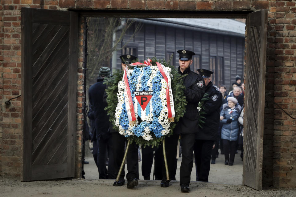 Security men carry a wreath in tribute to those who perished at the camp.