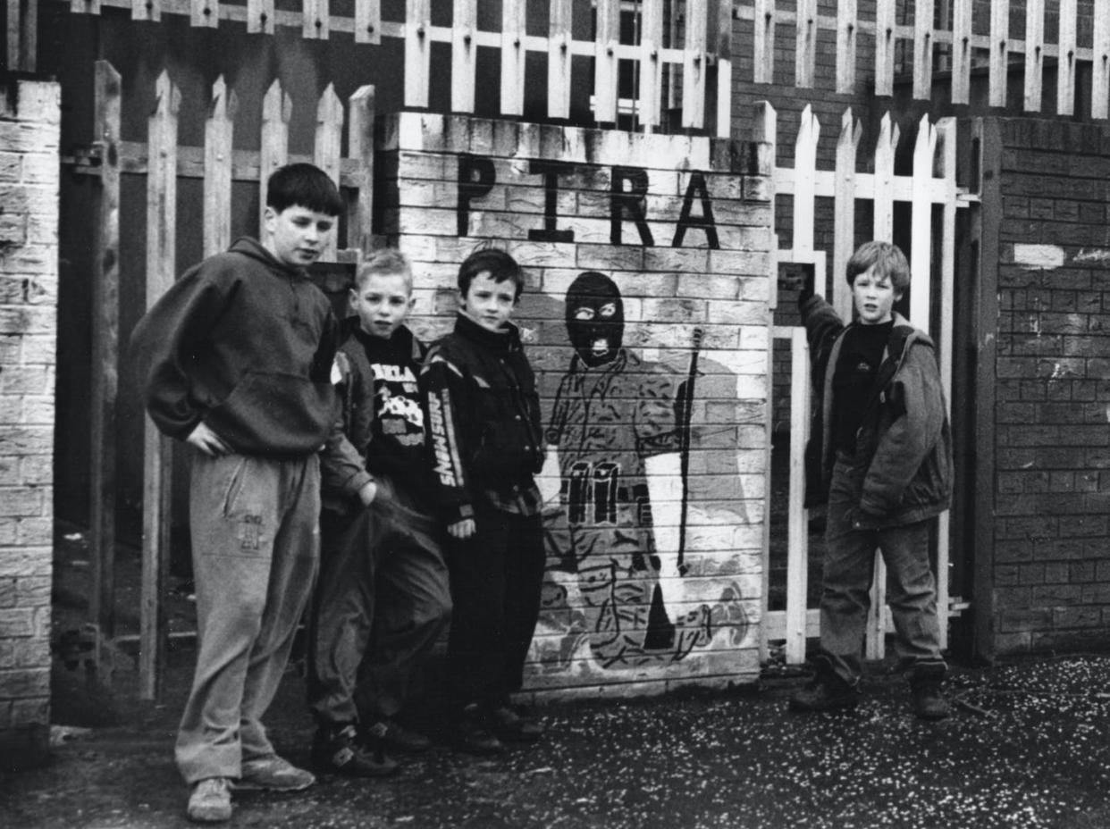 Niños posan junto a un mural callejero en honor a los miembros del IRA Provisional (PIRA), un grupo armado escindido del IRA, en Belfast. <a href="https://www.shutterstock.com/es/image-photo/west-belfast-northern-ireland-uk-march-1951583125" rel="nofollow noopener" target="_blank" data-ylk="slk:RORY NUGENT.com / Shutterstock;elm:context_link;itc:0;sec:content-canvas" class="link ">RORY NUGENT.com / Shutterstock</a>