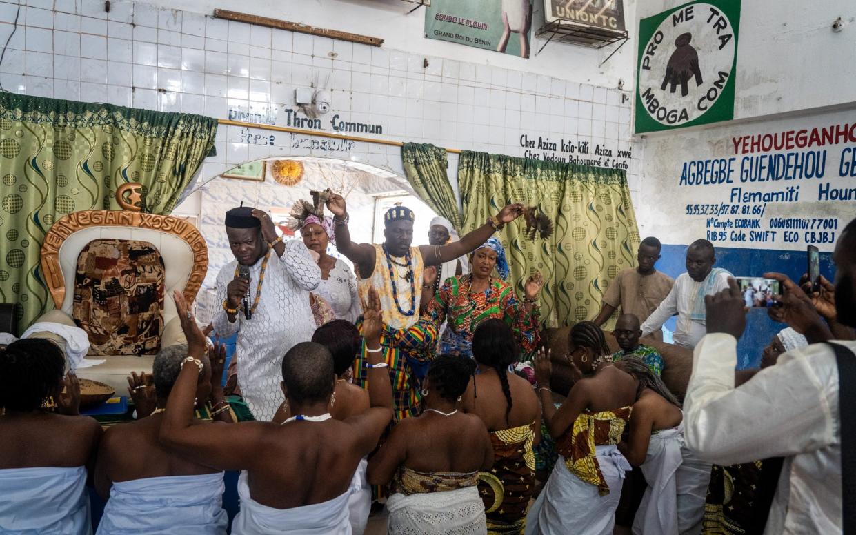 King Yehouegan Houssou Agbégbé II holds two small chicks in front of the congregation. They will later be sacrificed in honour of a deity called Thron