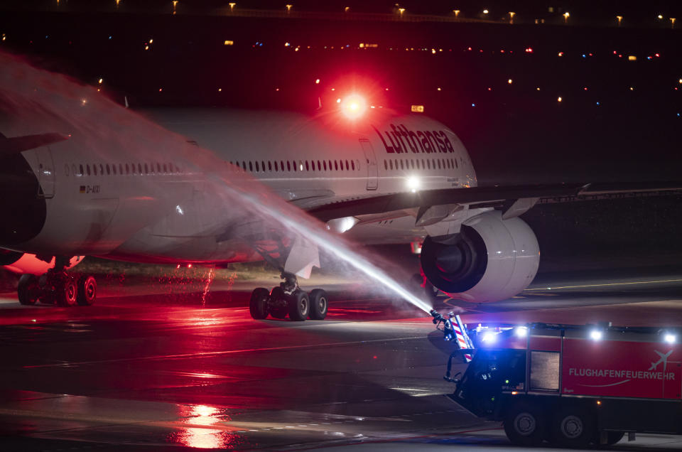 The last Lufthansa flight of the Airbus A350 aircraft from Tegel Airport is taxiing to the take-off field as it is bid farewell by the airport fire brigade with a fountain of water, in Berlin, Germany, Saturday, Nov. 7, 2020. The final flight is scheduled for Sunday. (Fabian Sommer/dpa via AP)