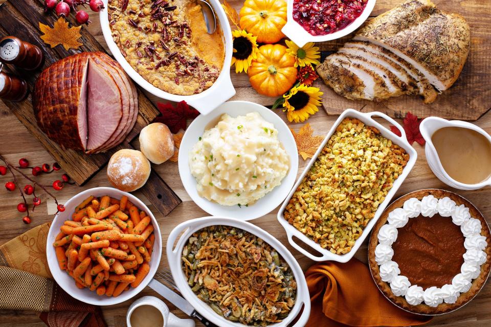 Thanksgiving table with roasted turkey, sliced ham and side dishes