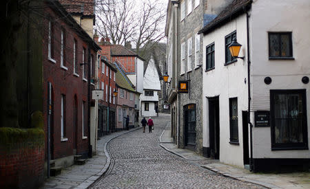 People walk along a cobbled street in Norwich, Britain, March 20, 2018. REUTERS/Hannah McKay/Files