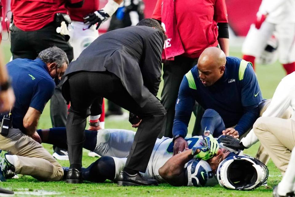 An injured Seattle Seahawks free safety Quandre Diggs grimaces as he is attended to by Seahawks training and medical staff during the second half of an NFL football game against the Arizona Cardinals Sunday, Jan. 9, 2022, in Glendale, Ariz. (AP Photo/Darryl Webb)