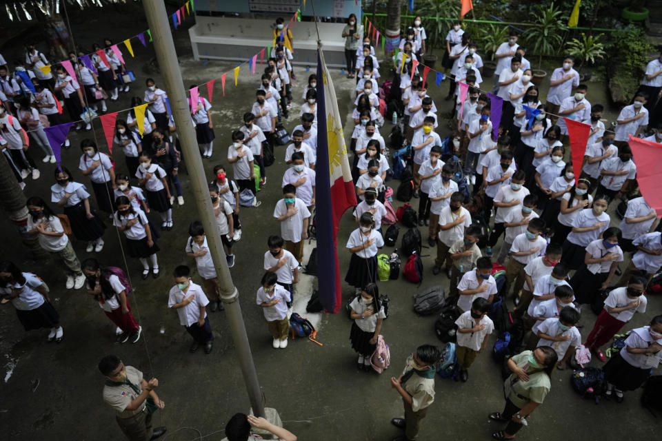 Students attend a flag raising ceremony during the opening of classes at the San Juan Elementary School in metro Manila, Philippines on Monday, Aug. 22, 2022. Millions of students wearing face masks streamed back to grade and high schools across the Philippines Monday in their first in-person classes after two years of coronavirus lockdowns that are feared to have worsened one of the world's most alarming illiteracy rates among children. (AP Photo/Aaron Favila)